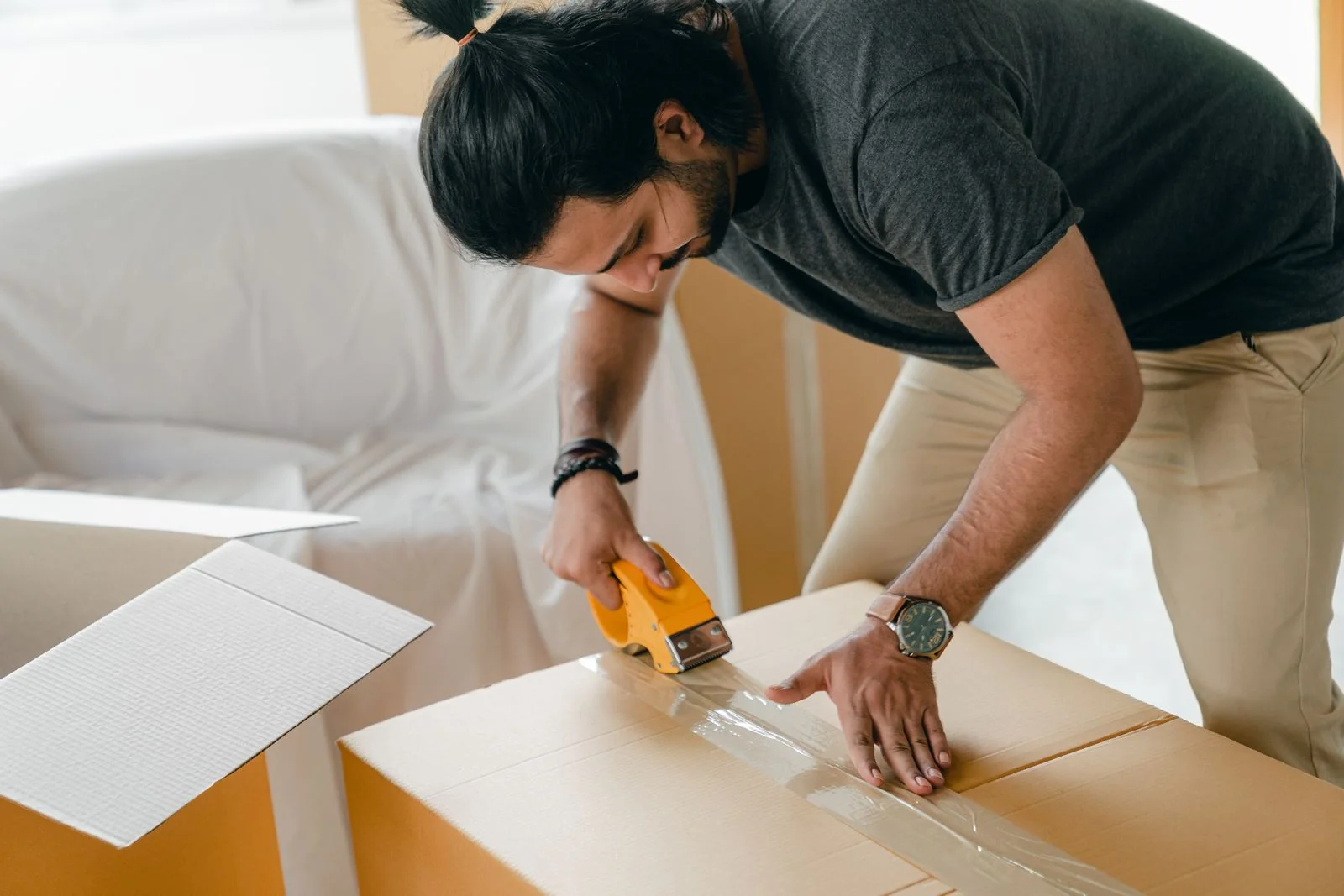 Illustrative close-up of a man carefully sealing a moving box